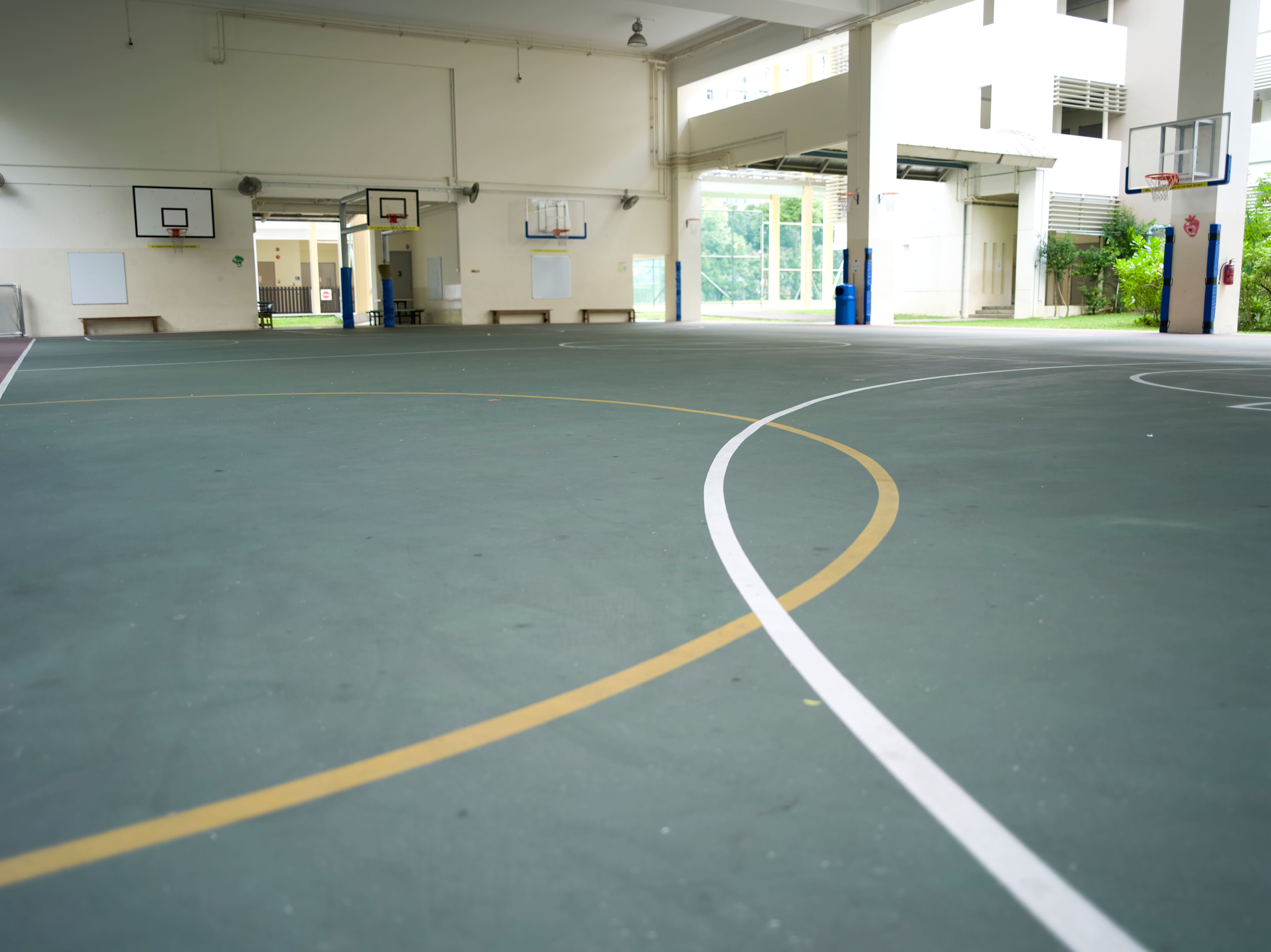 Covered school basketball court with multiple basketball hoops.